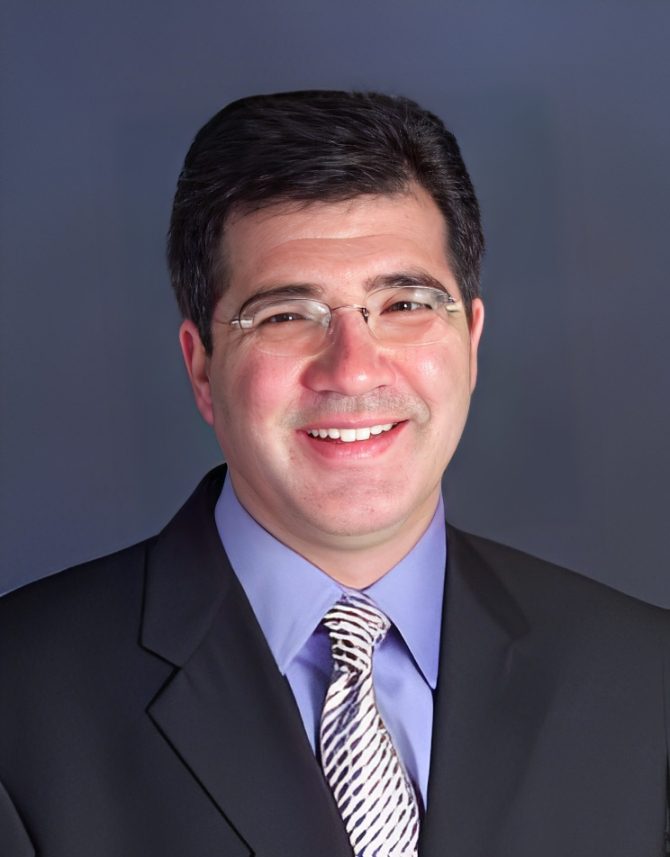 Smiling man in suit and glasses.