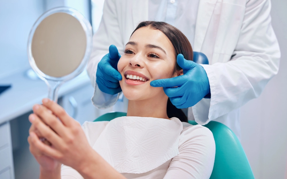 Woman smiling at dentist holding mirror.